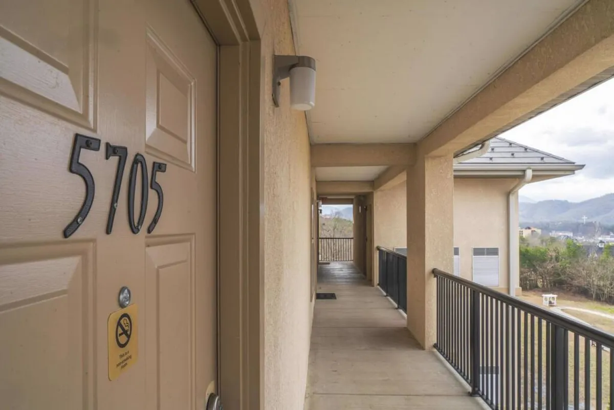 A welcoming corridor with a clearly marked door number 5705, a modern light fixture, and a sturdy railing. The entryway exudes a sense of anticipation and security, setting the stage for a stress-free arrival experience.