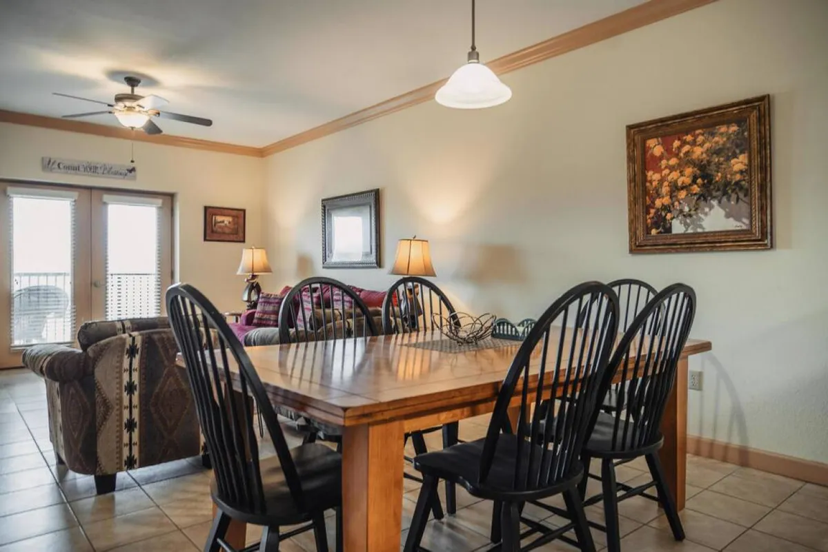 A cozy living-dining space featuring a dining table, plush sofa, wall art, and lamps. The arrangement promotes warmth and togetherness, suitable for dinners, socializing, and relaxing.