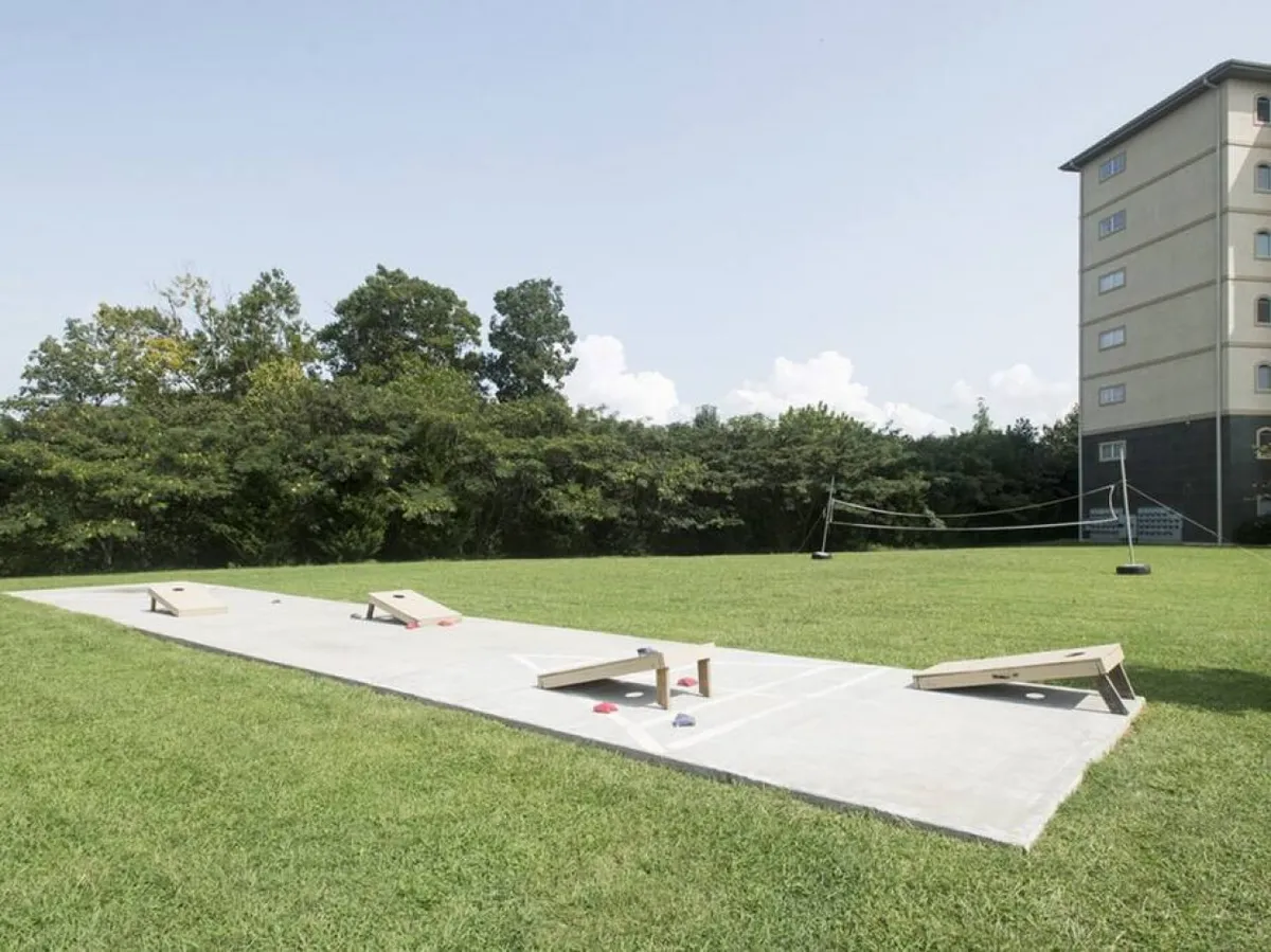 A lush green area featuring cornhole boards, perfect for friendly family competitions or group gatherings. The background includes a glimpse of the resort building, reinforcing the community feel and offering a sense of place within the resort grounds.